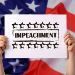 Hands holding impeachment sign over American flag.