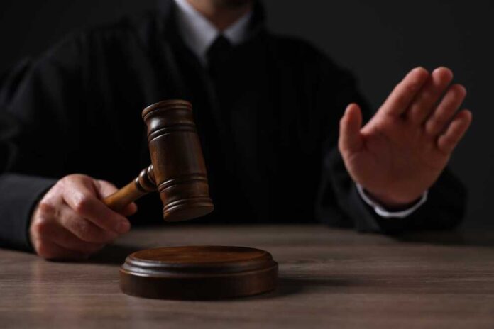 shutterstock_2381854215.jpg featured image Judge holding gavel, hand raised in courtroom.