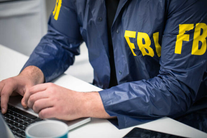 shutterstock_629482379.jpg featured image Person in FBI jacket working on laptop.