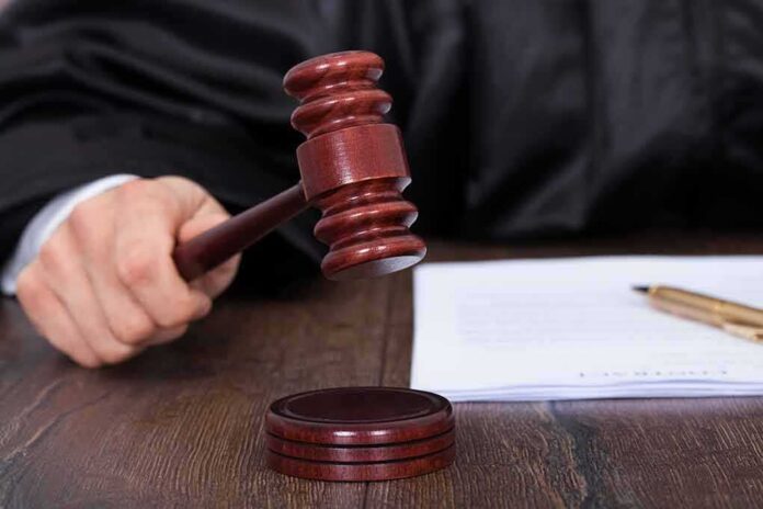 186812807 featured image Judge's hand holding gavel next to documents.