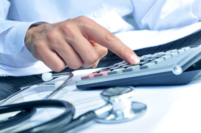shutterstock_281844725.jpg featured image Doctor using calculator with stethoscope on the table.