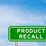 Green sign with product recall text and sky background