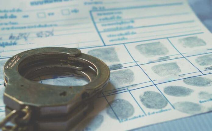 shutterstock_2291869477.jpg featured image Handcuffs on a fingerprint document.