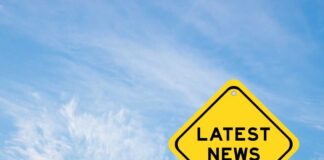 Yellow sign with latest news text against sky