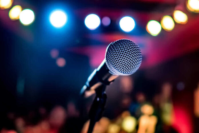 shutterstock_1017257791.jpg featured image Microphone with colorful stage lights in the background.