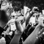Raised fists at a protest rally, black and white image.