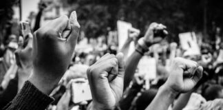 Raised fists at a protest rally, black and white image.