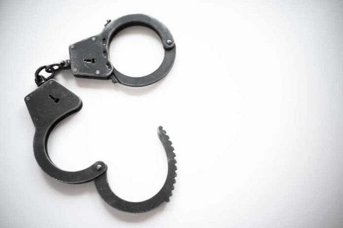 Open metal handcuffs on white background.