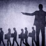 Shadows of laid-off workers walking, large figure pointing.