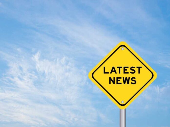 Yellow sign with latest news text against sky