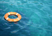 Orange life ring floating in clear blue water.