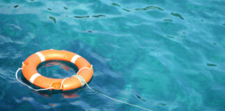 Orange life ring floating in clear blue water.