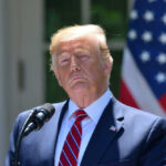 Donald Trump speaking with US flag in the back