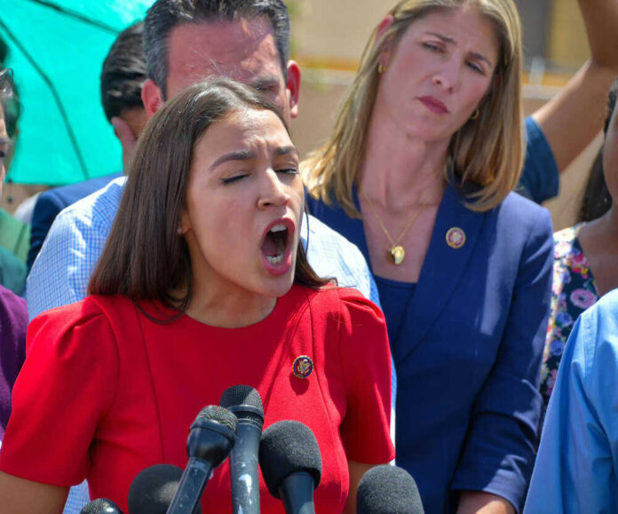 shutterstock_1439783054.jpg Alexandria Ocasio-Cortez speaking passionately at microphones.