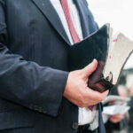 Man in suit holding a worn Bible
