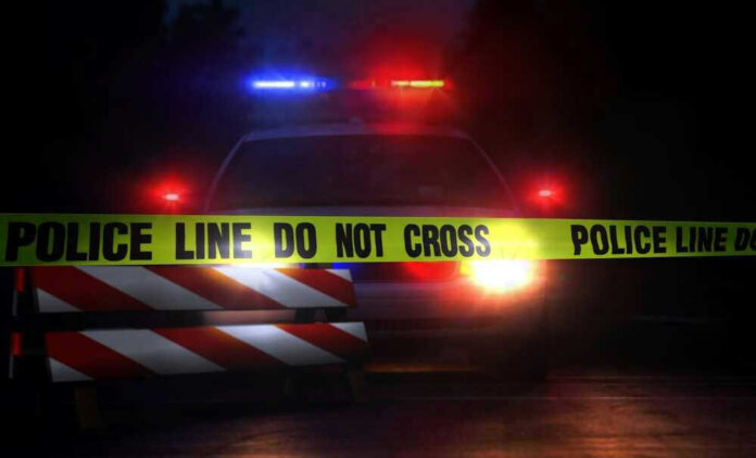 shutterstock_693454099.jpg Police car with flashing lights behind caution tape