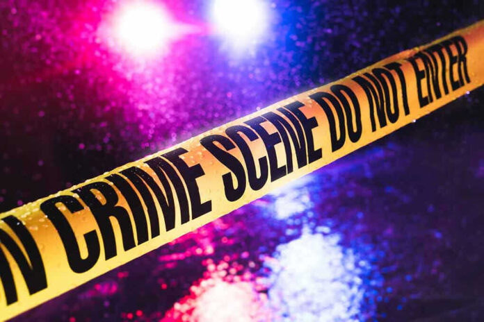 Crime scene tape with flashing lights in background
