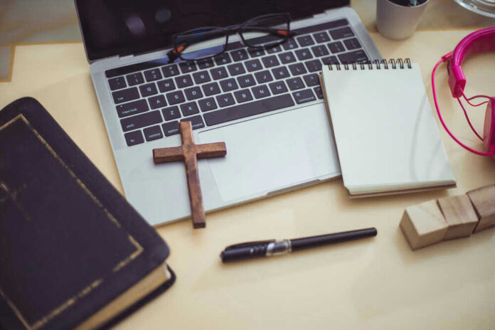Bible, cross, laptop, notebook, pen, and pink headphones