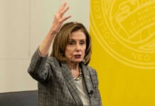 Nancy Pelosi gestures while speaking in front of yellow backdrop