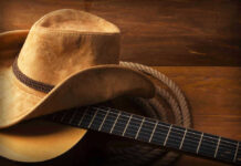 Cowboy hat on guitar next to coiled rope