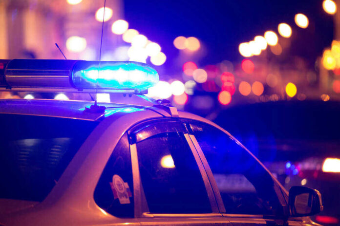 shutterstock_4489971131.jpg Police car with flashing blue lights at night