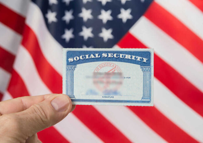 Hand holding social security card, American flag background