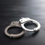 20-Year-Old Murder Solved – Shock Arrest! Metal handcuffs on a dark textured surface.