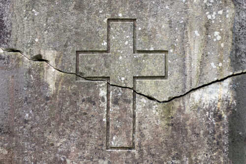 Close-up of a weathered gravestone with a carved cross