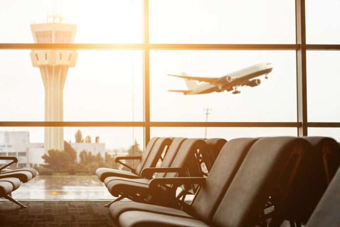 View of an airport terminal with an airplane taking off in the background
