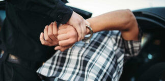 Person in handcuffs arrested by police officer.