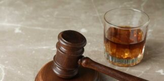 A wooden gavel next to a glass of whiskey with ice