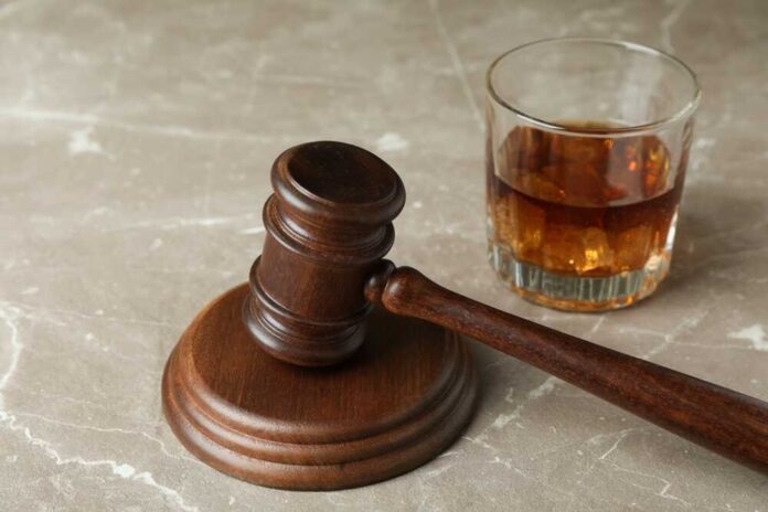 A wooden gavel next to a glass of whiskey with ice
