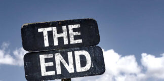 A weathered sign displaying the words 'THE END' against a cloudy sky