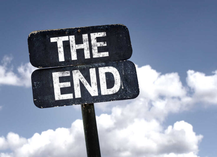 A weathered sign displaying the words 'THE END' against a cloudy sky