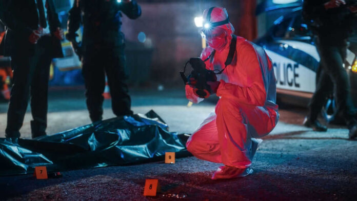 Forensic investigator examines crime scene at night.