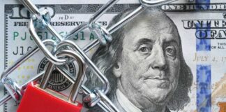A red padlock and chain over a hundred dollar bill featuring Benjamin Franklin