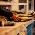 A vendor handling fresh fish at a market stall