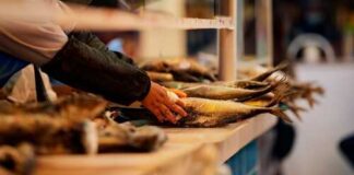 A vendor handling fresh fish at a market stall