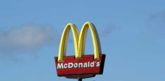 McDonalds drive-thru sign against a blue sky.
