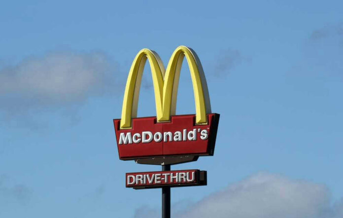McDonalds drive-thru sign against a blue sky.