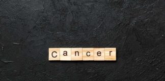 Wooden letters spelling the word 'Cancer' on a black textured background