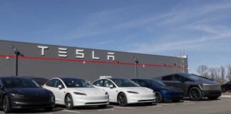 A lineup of Tesla cars parked in front of a Tesla building