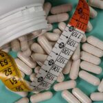 White capsules scattered around a measuring tape and a bottle