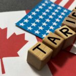 100% Tariff Warning: Trump Targets Canadian Goods Wooden blocks spelling 'TARIFFS' on flags of Canada and the USA