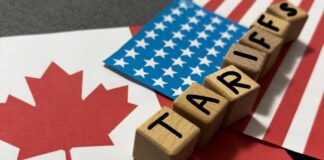 Wooden blocks spelling 'TARIFFS' on flags of Canada and the USA