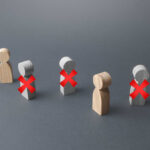 Massive Layoff Wave Hits Lib Newspaper Wooden figures representing people with red crosses indicating exclusion