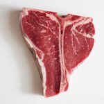 Raw T-bone steak on a white background