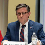 Speaker Johnson SLAMS Democrats Latest Tactic Mike Johnson in a suit speaks into a microphone.