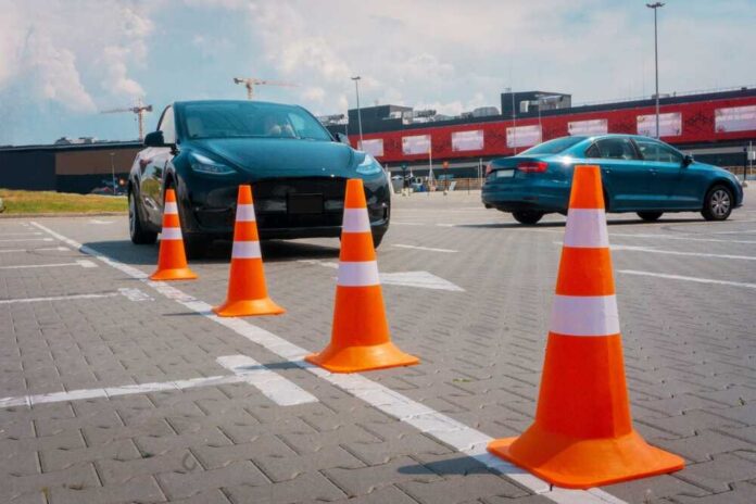 shutterstock_2604417599.jpg A black electric car parked near orange traffic cones in a parking lot