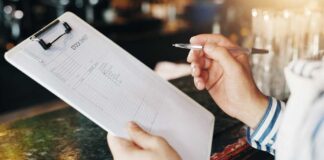 Person holding a stock sheet on a clipboard with a pen